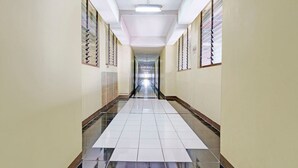 Un pasillo largo y estrecho con pisos y paredes de baldosas, que conduce a un extremo luminoso.