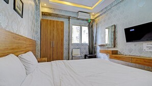 Un dormitorio con una cama grande, un armario de madera, un escritorio pequeño y un televisor en la pared.