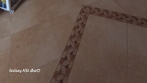 Un vestíbulo de hotel con una pantalla grande mostrando un programa, una pared decorativa de rocas, una planta en maceta y un cuadro de una catedral.