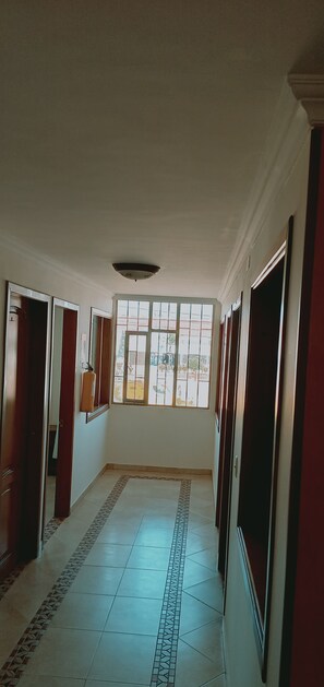 A hallway with tiled flooring, a large window, and doors leading to rooms. - San gabriel (Ubaté)