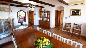 A dining area with a wooden table, white chairs, and a chandelier. There is a cabinet with glass doors and a mirror on the wall. - Villa with swimming pool & barbecue, sea view on Capri, Amalfi Coast 20 min away (Massa Lubrense)