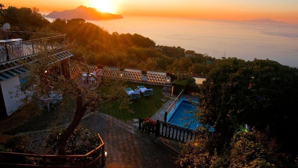 A resort with a swimming pool, lounge chairs, and a view of the sunset over the ocean. - Villa with swimming pool & barbecue, sea view on Capri, Amalfi Coast 20 min away (Massa Lubrense)