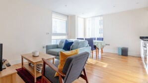 Un grand espace de vie comprenant un canapé, une table basse en bois et une table à manger avec des chaises.