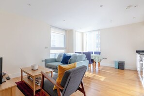 Un grand espace de vie comprenant un canapé, une table basse en bois et une table à manger avec des chaises.