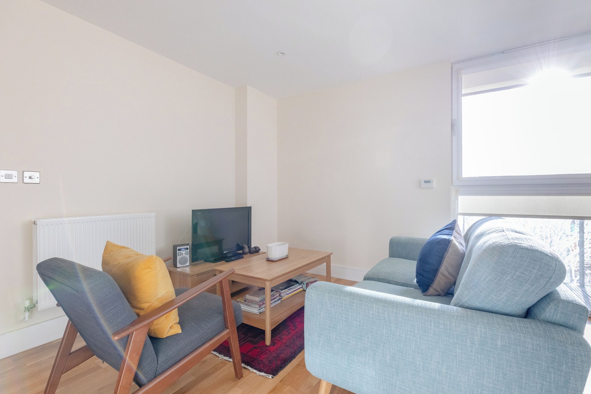 A modern living room with a sofa, armchair, and a small table with a television.