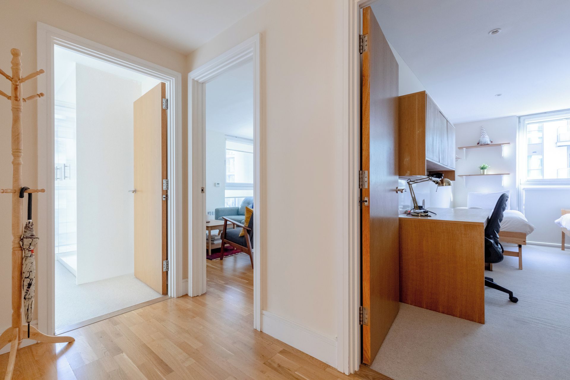 Une porte ouverte donne sur un espace de vie comprenant un canapé, un bureau avec une lampe et une chaise.