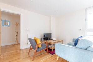 A modern living room with a sofa, a chair, a coffee table, and a television. - Mid Century 2 BDR Private Balcony Canary (London)