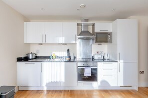 Une cuisine moderne avec des armoires blanches, des appareils en acier inoxydable et un four à micro-ondes encastré.