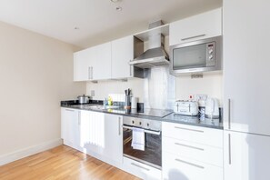 A modern kitchen with white cabinets, stainless steel appliances, a built-in oven, and a microwave. - Mid Century 2 BDR Private Balcony Canary (London)