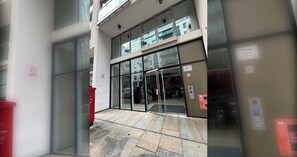A building entrance with glass doors, a red trash bin, and a sign indicating 'Cobalt Point.' - Mid Century 2 BDR Private Balcony Canary (London)