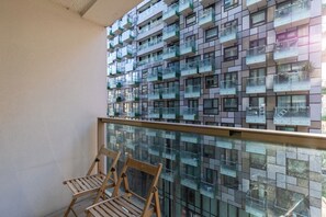 A balcony with a glass railing and wooden chairs. - Mid Century 2 BDR Private Balcony Canary (London)