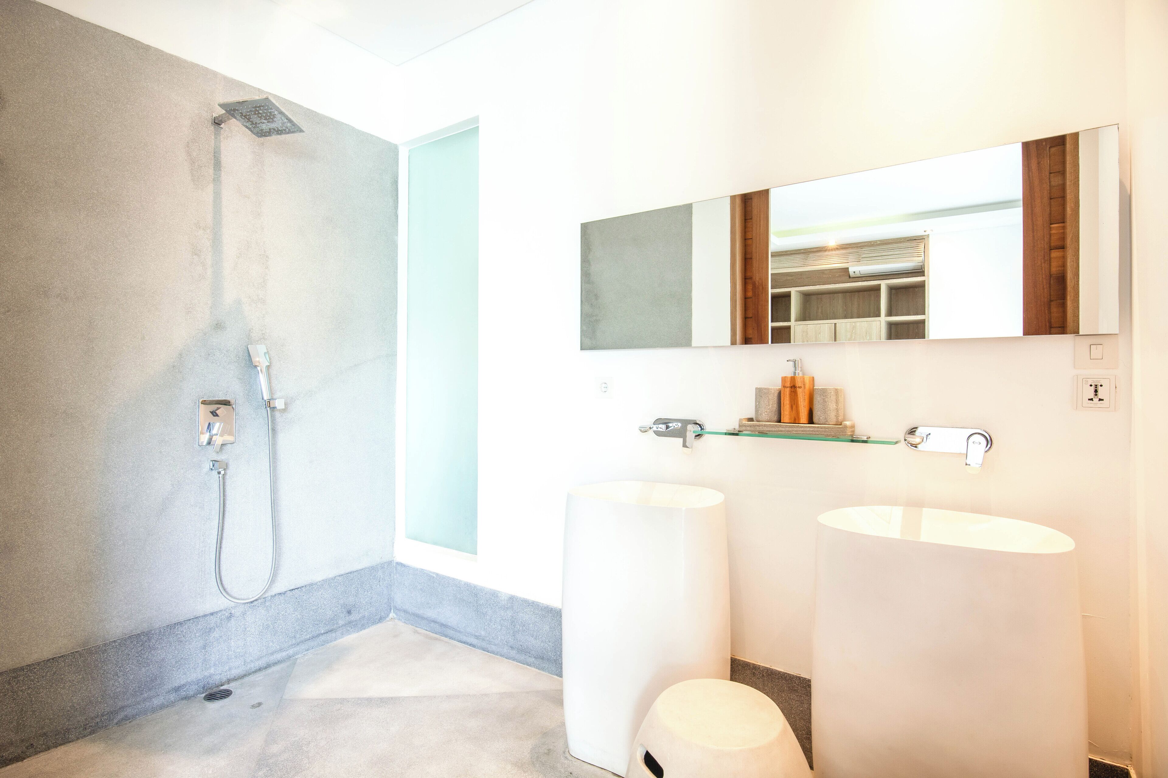 A modern bathroom with a shower, two sinks, and a large mirror.