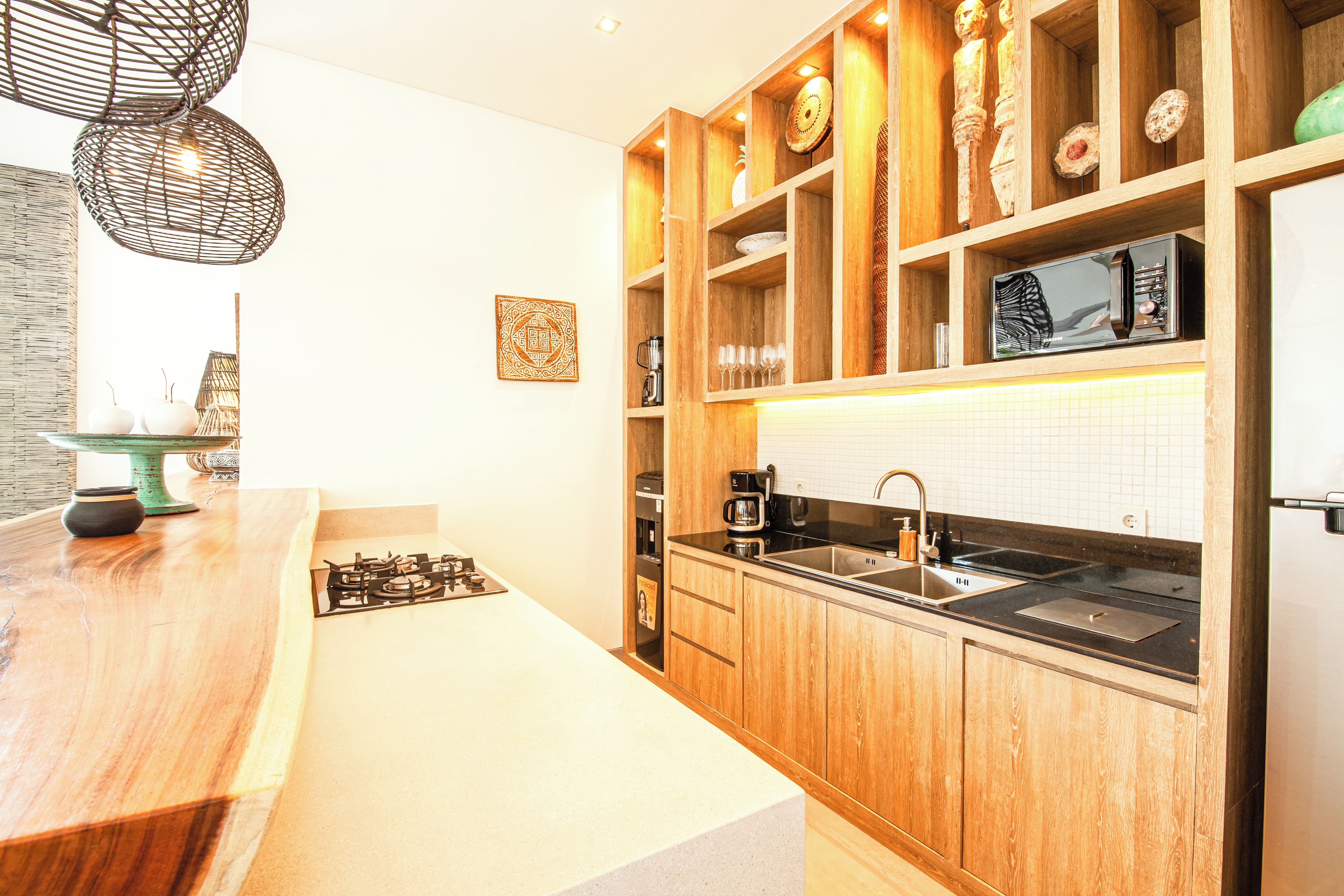 Une cuisine moderne avec des meubles en bois, un évier en acier inoxydable et un four à micro-ondes encastré.