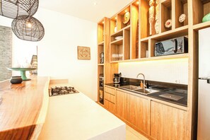 A modern kitchen with wooden cabinets, a stainless steel sink, and a built-in microwave. - Chic 2BR Villas, Brawah Hub, 300m to Coastal Bliss (Canggu)