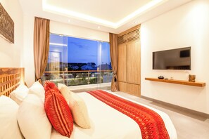 A modern bedroom with a large bed, a TV, and a balcony with a city view. - Chic 2BR Villas, Brawah Hub, 300m to Coastal Bliss (Canggu)