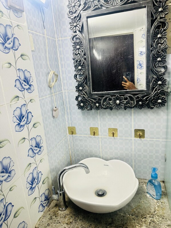 A bathroom with a white sink, a mirror with an ornate frame, and floral-patterned tiles. - Beautiful 1-bed Studio in Dhaka (Dhaka)