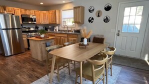 Una cocina moderna con armarios de madera, electrodomésticos de acero inoxidable y un comedor con mesa y sillas de madera.