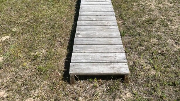 Una pasarela de madera que conduce a una playa con cielos despejados.