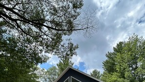 Una casa de dos pisos con un balcón, ventanas amplias y un patio cubierto.