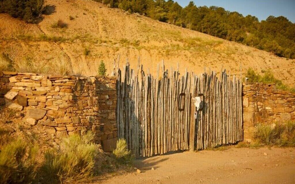 A rustic stone wall with a wooden fence and a gate.