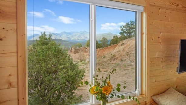 Habitació amb un gran finestral que ofereix vistes a muntanyes i arbres.