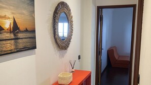 A hallway with a red console table, a decorative mirror, and a painting of a sunset over water. - Baia - With a bay View (Alcobaça)