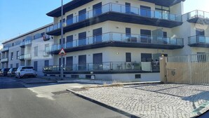 A multi-story building with balconies, a gated entrance, and a cobblestone driveway. - Estrela do Mar - Com Vista Para a Piscina (Alcobaça)
