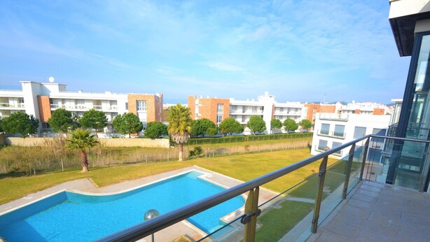 A residential building with a swimming pool, a balcony with a glass railing, and a clear view of the surrounding neighborhood. - Estrela do Mar - Com Vista Para a Piscina (Alcobaça)