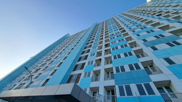 A high-rise building with a modern architectural design, featuring a grid of windows and balconies. - OYO Life 93106 Apartement Grand Sentraland By Andi (Karawang)