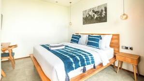 A modern bedroom with a wooden bed, a bedside table, a chair, and a wall-mounted artwork. - New 4BR Villa 200m to the Beach Canggu (Munggu)