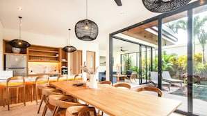 A modern kitchen with wooden cabinets, a large island, and pendant lighting. - New 4BR Villa 200m to the Beach Canggu (Munggu)