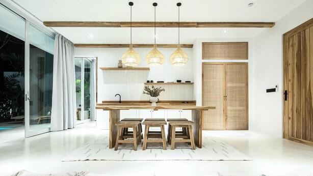 Une cuisine moderne avec un îlot central en bois, des luminaires suspendus et une grande porte coulissante.