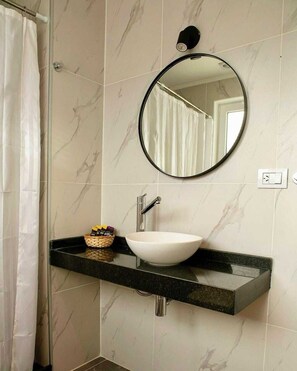 A bathroom with a white sink, a round mirror, and a shower curtain.