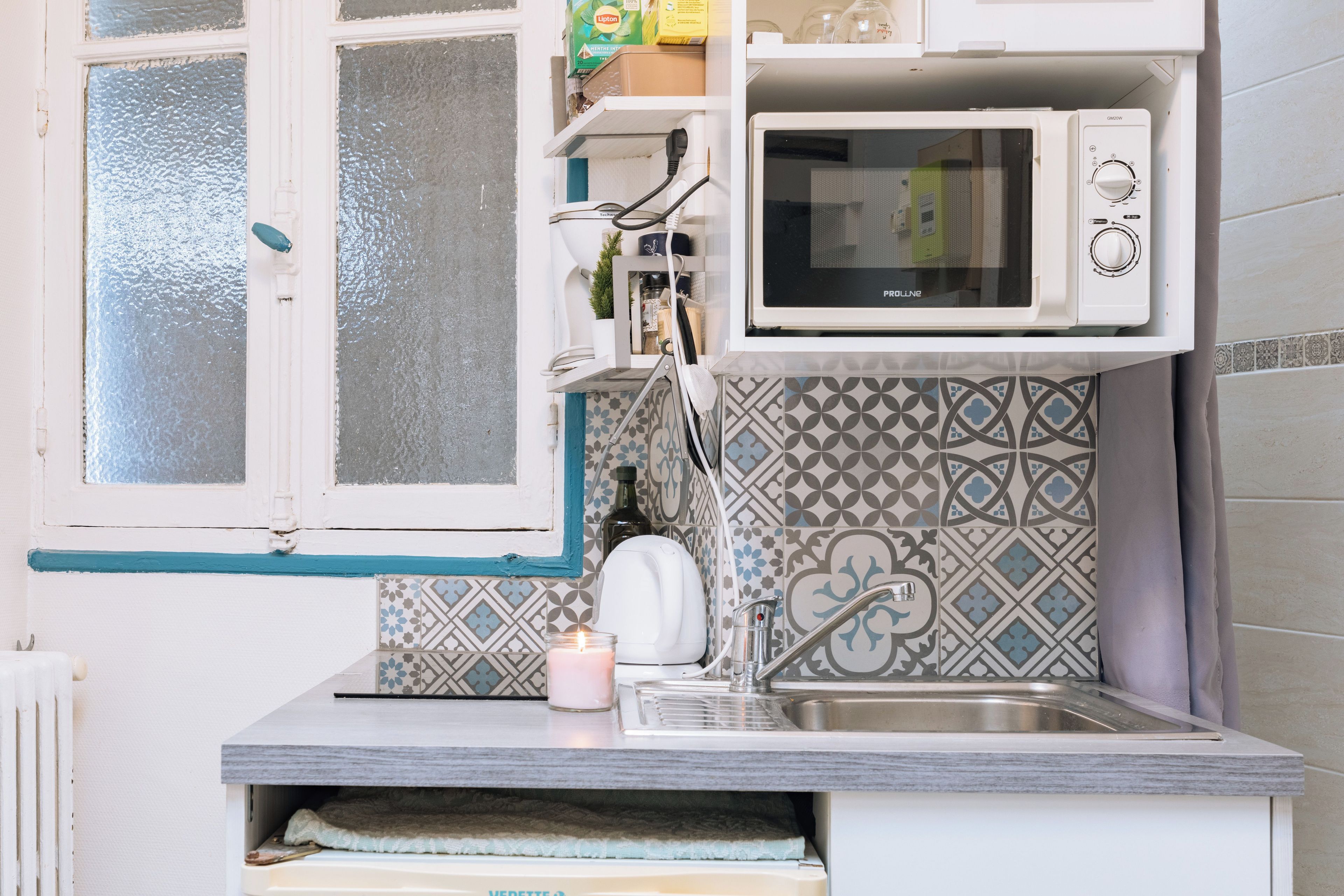 A compact kitchen with a microwave, a kettle, and a sink.