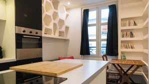 Une cuisine moderne dotée d’un îlot central, d’un four encastré et d’un coin repas avec une table et des chaises en bois.