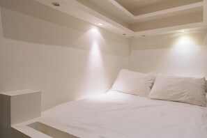 A minimalist bedroom with a bed, white walls, and recessed ceiling lighting. - Perfect Studio Getaway for Lovers & Solo Explorers (Paris)