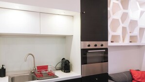 Cocina moderna con un lavamanos de acero inoxidable, una cafetera y un horno empotrado.