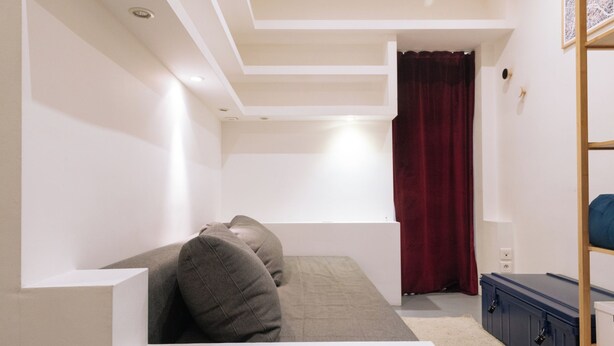 Una habitación con una cama, una cortina roja y un mueble azul.