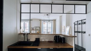 Een moderne keuken met een houten aanrecht, zwarte kastjes, een spoelbak en een koffieapparaat.