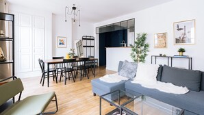 Een moderne woonkamer met een bank, eettafel, stoelen en een glazen salontafel.