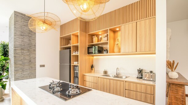 Une cuisine moderne dotée d’un îlot central, de meubles en bois et d’appareils électroménagers intégrés.