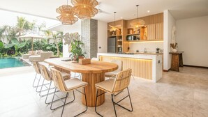 Une cuisine moderne dotée d’un îlot central, de meubles en bois et de luminaires suspendus.