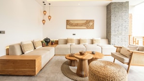 Un salon moderne avec un canapé d’angle, une table basse en bois et des tables d’appoint en osier.