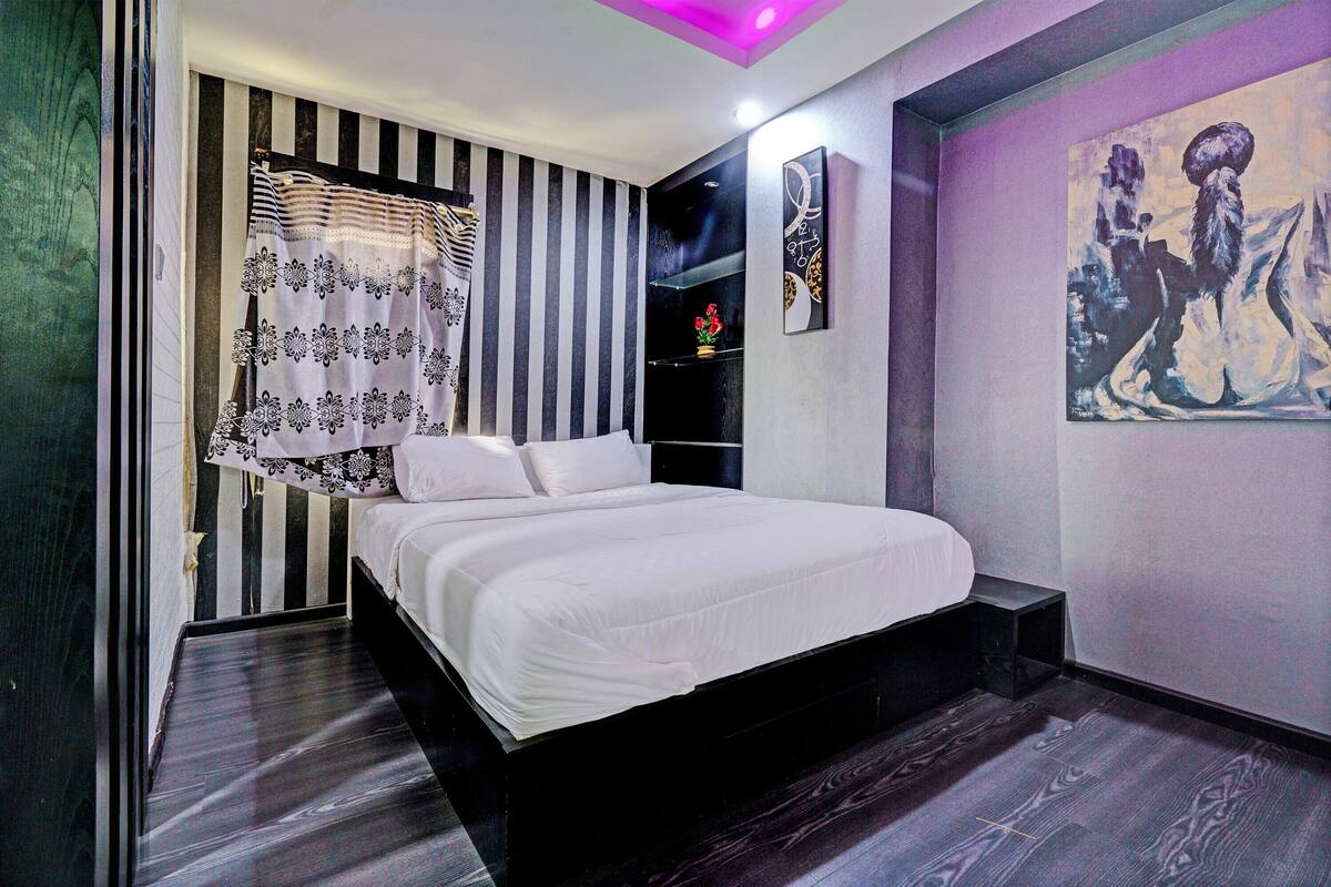 Ein modernes Schlafzimmer mit einem großen Bett, Streifenmuster-Tapete und einem Gemälde an der Wand.