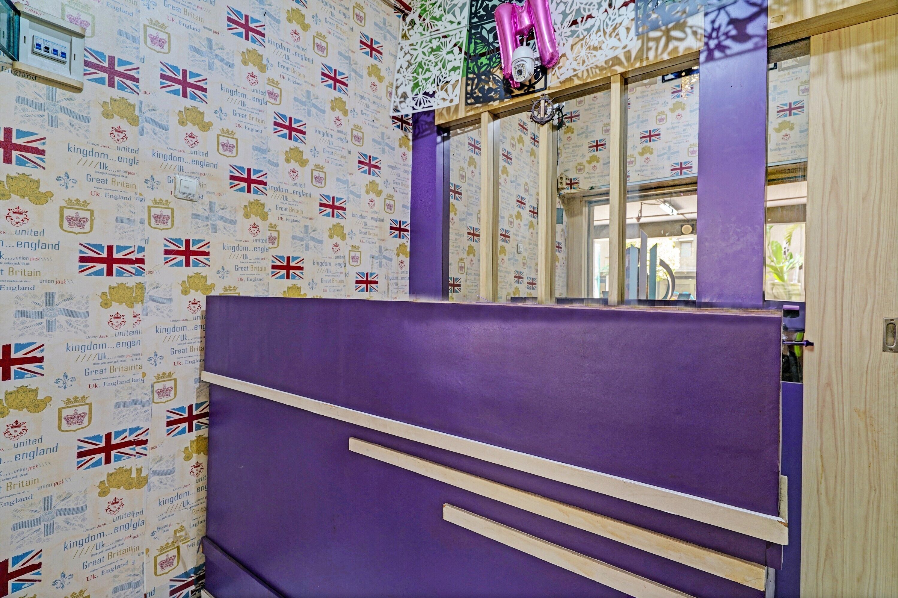 A room with a purple partition, a window with a view, and a wall decorated with the UK flag and text.
