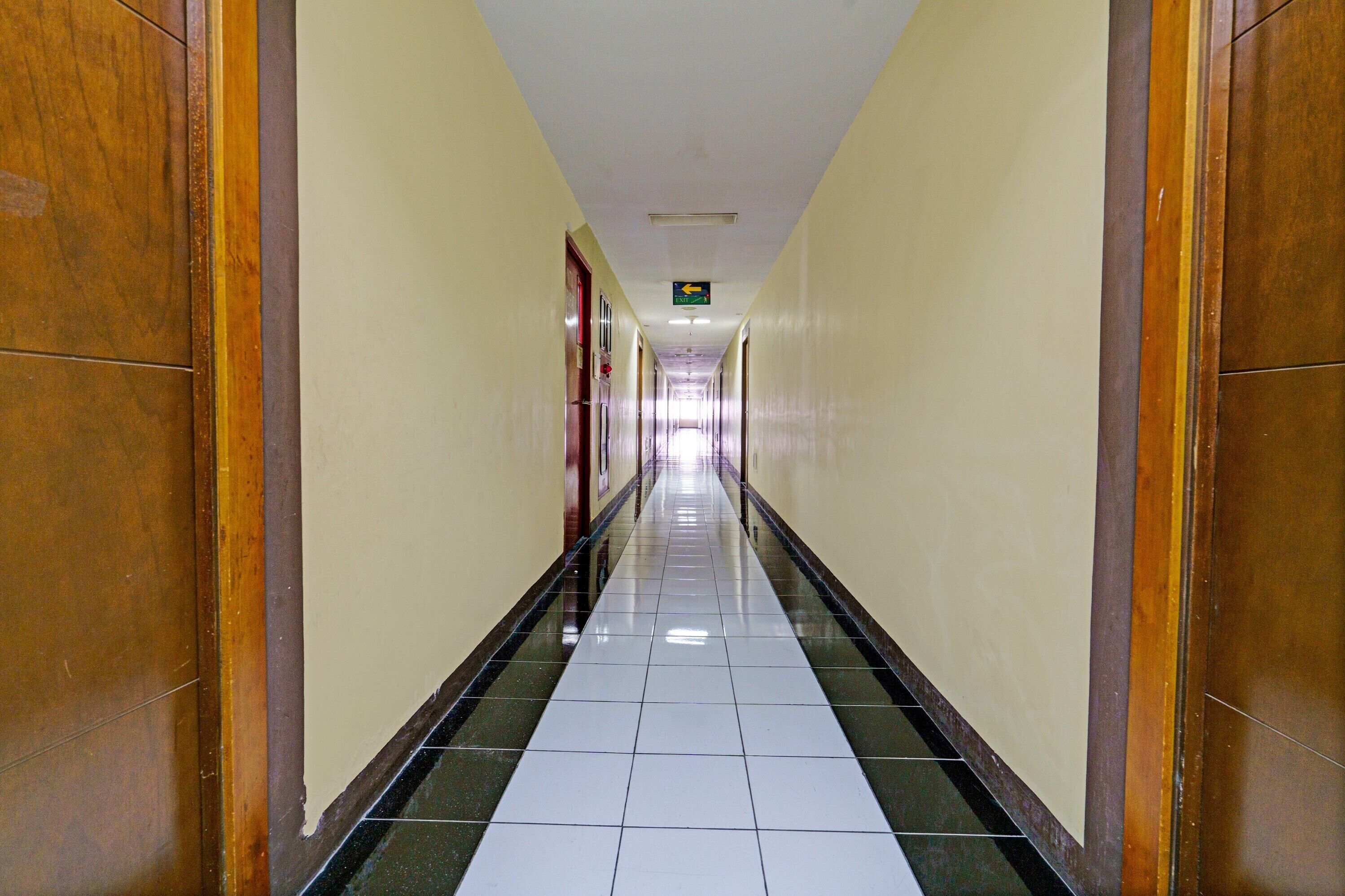 A long, narrow hallway with a tiled floor and wooden doors on either side.