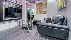 Een moderne woonkamer met een grote flatscreen televisie, een leren bank en een glazen salontafel.