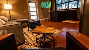 Un salon chaleureux avec un canapé, une table basse en bois et un téléviseur fixé au mur.