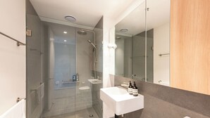 Ein modernes Badezimmer mit einer Duschkabine aus Glas, einem weißen Waschbecken und einem großen Spiegel.