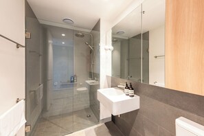 Une salle de bain moderne avec une douche à parois de verre, un lavabo blanc et un grand miroir.
